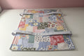 A patchwork fabric casserole carrier laying flat on a white table. 