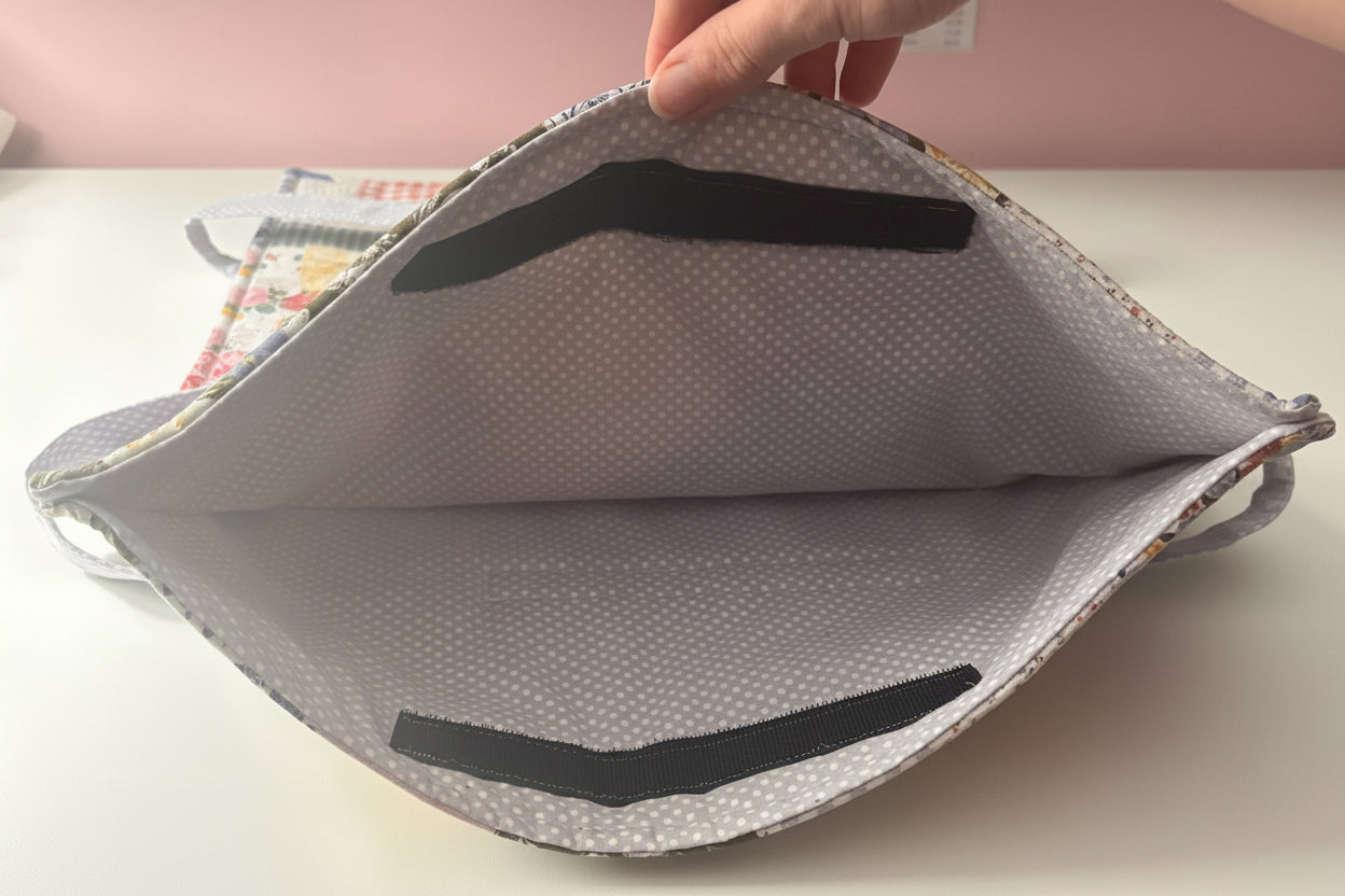 An opened casserole carrier, showing a purple with polka dots interior and a Velcro closure. 
