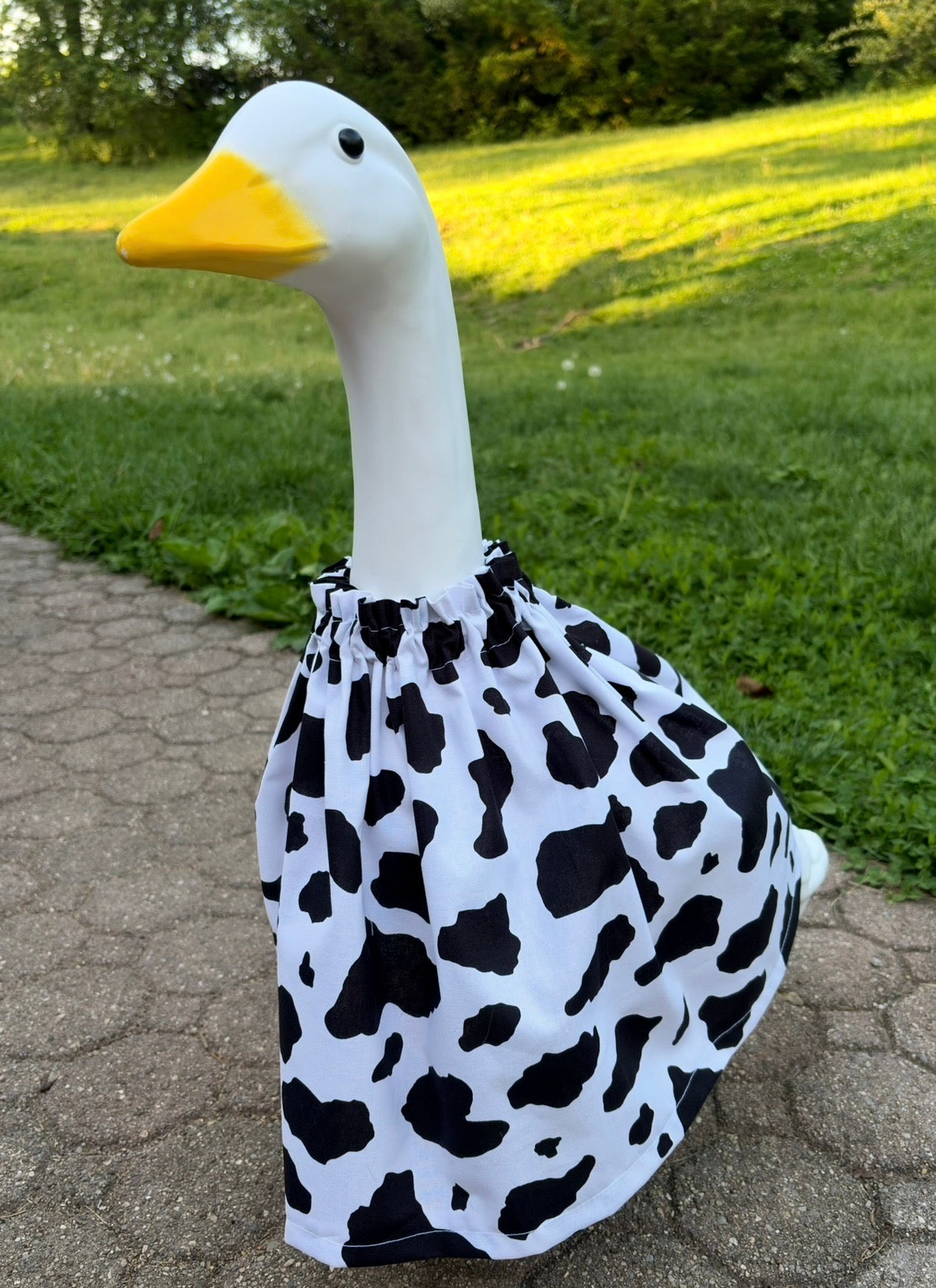 white porch goose wearing a cow print dress on a grassy background