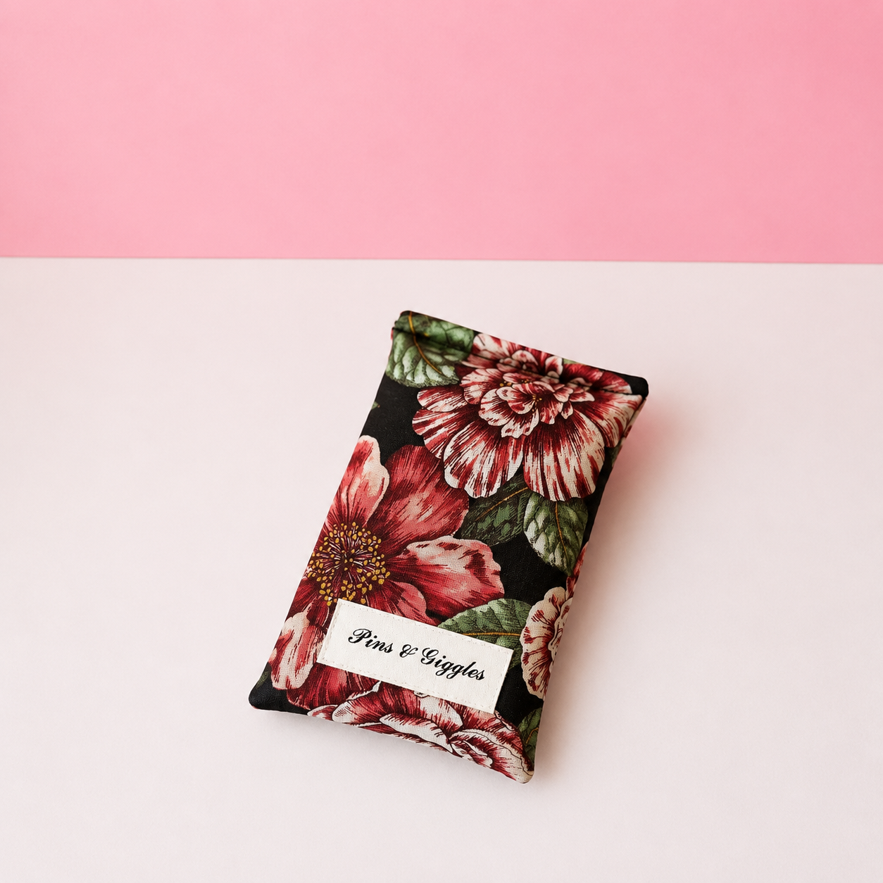 Floral patterned pouch with 'Pins & Giggles' label on a white and pink background