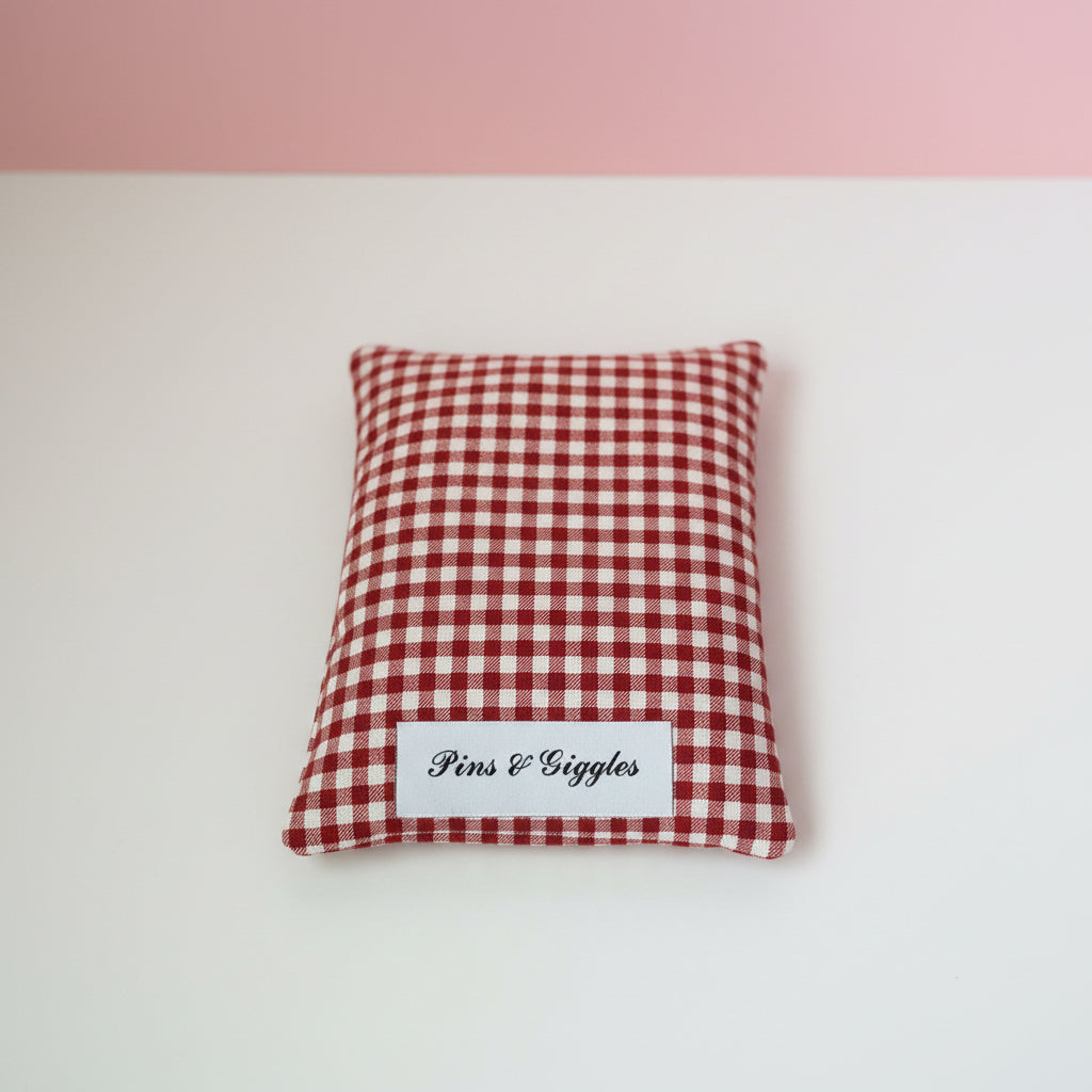 Red and white checkered pouch with 'Pins & Giggles' label on a white surface.