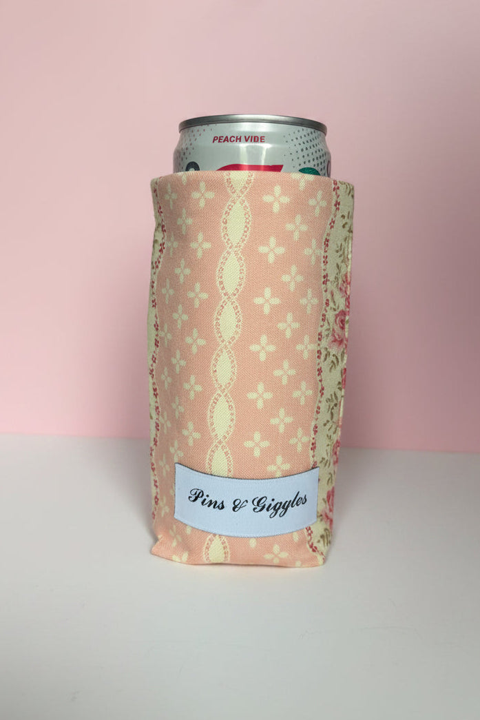 Can cooler with pink floral pattern and 'Pins & Giggles' label on a pink background