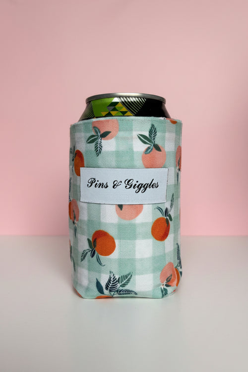 Can cooler with peach pattern and 'pins & Giggles' label on a pink background