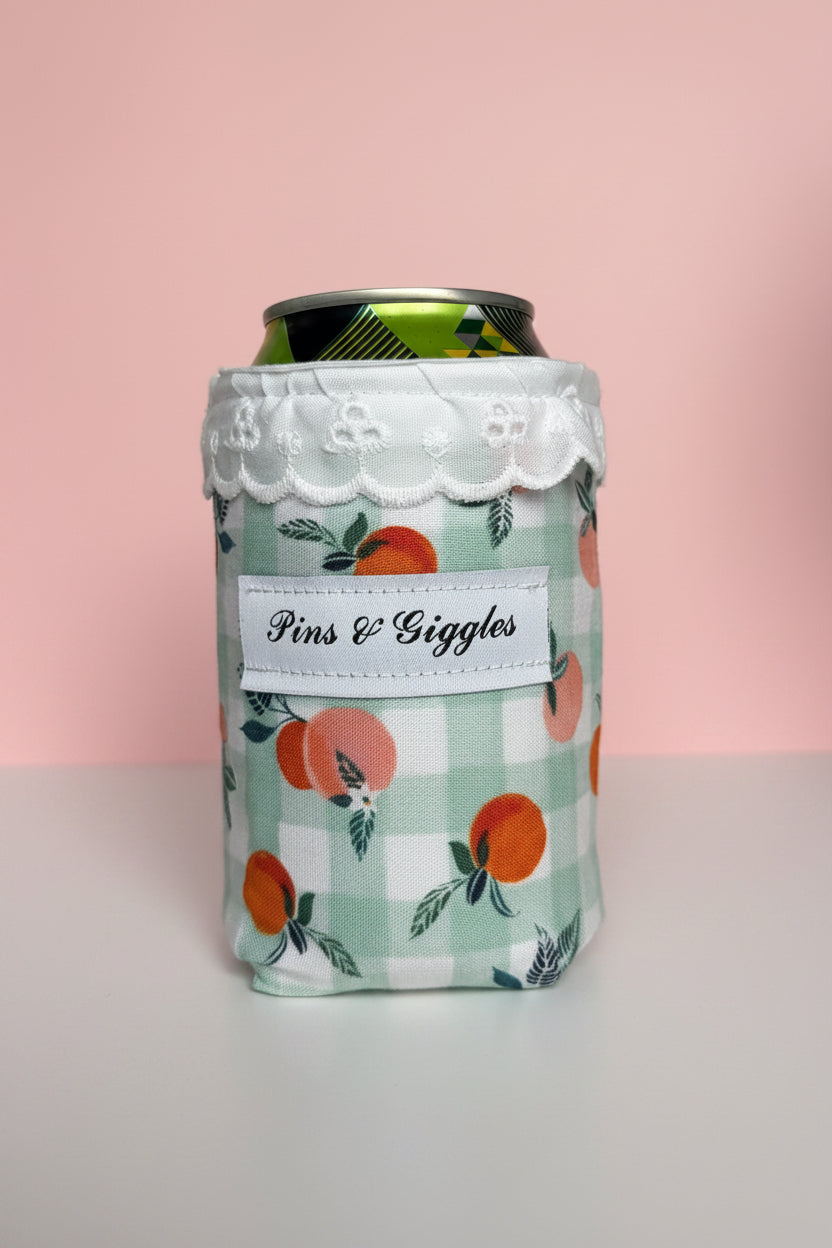 Can cooler with floral design and 'Pins & giggles' label on a pink background
