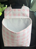 car trash can with pink checkered fabric hanging on the back of a car seat.