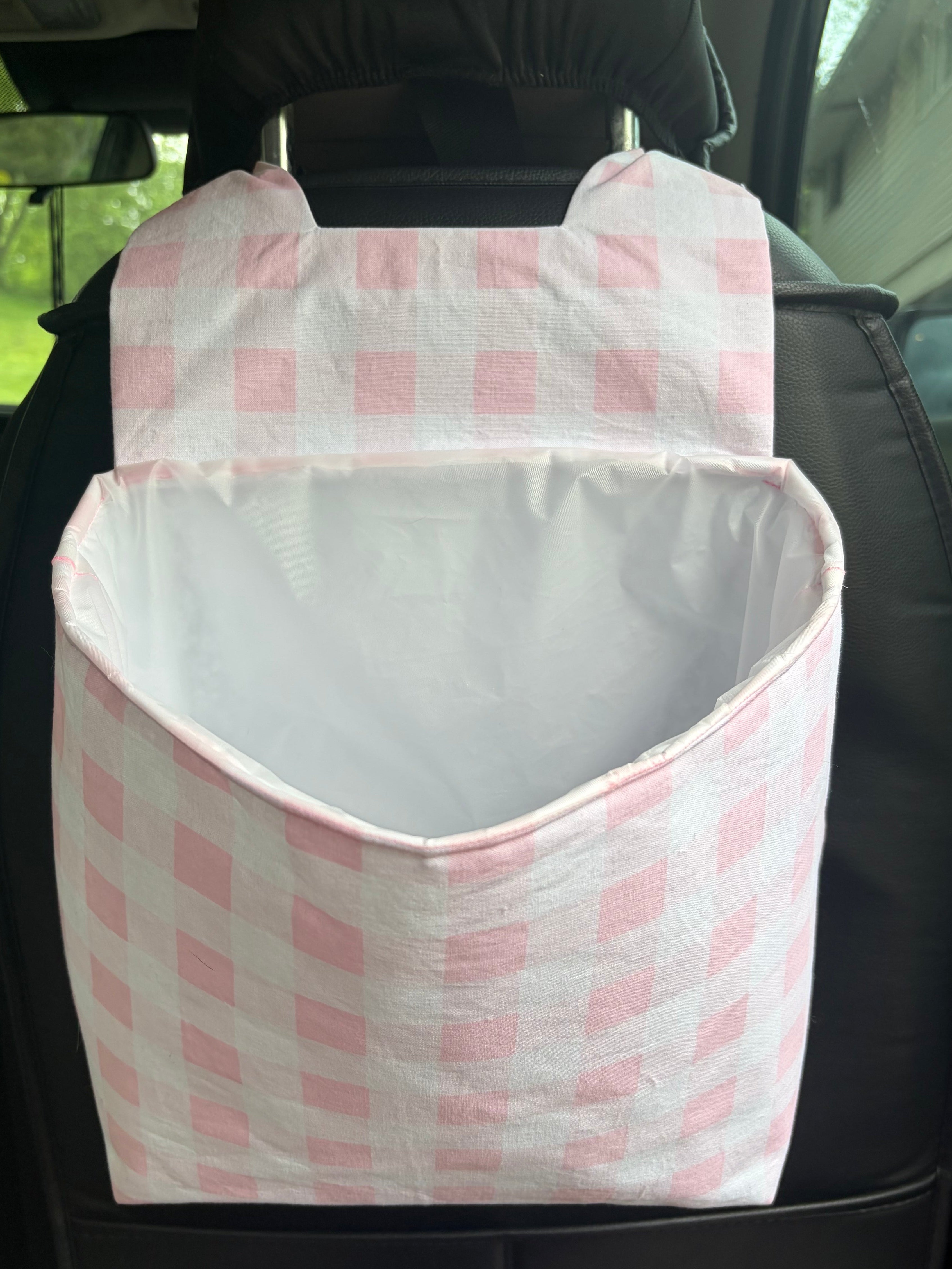 car trash can with pink checkered fabric hanging on the back of a car seat.