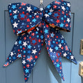 Large blue bow with star pattern on a blue door. Other side of bow has halloween or pumpkin themed fabric.