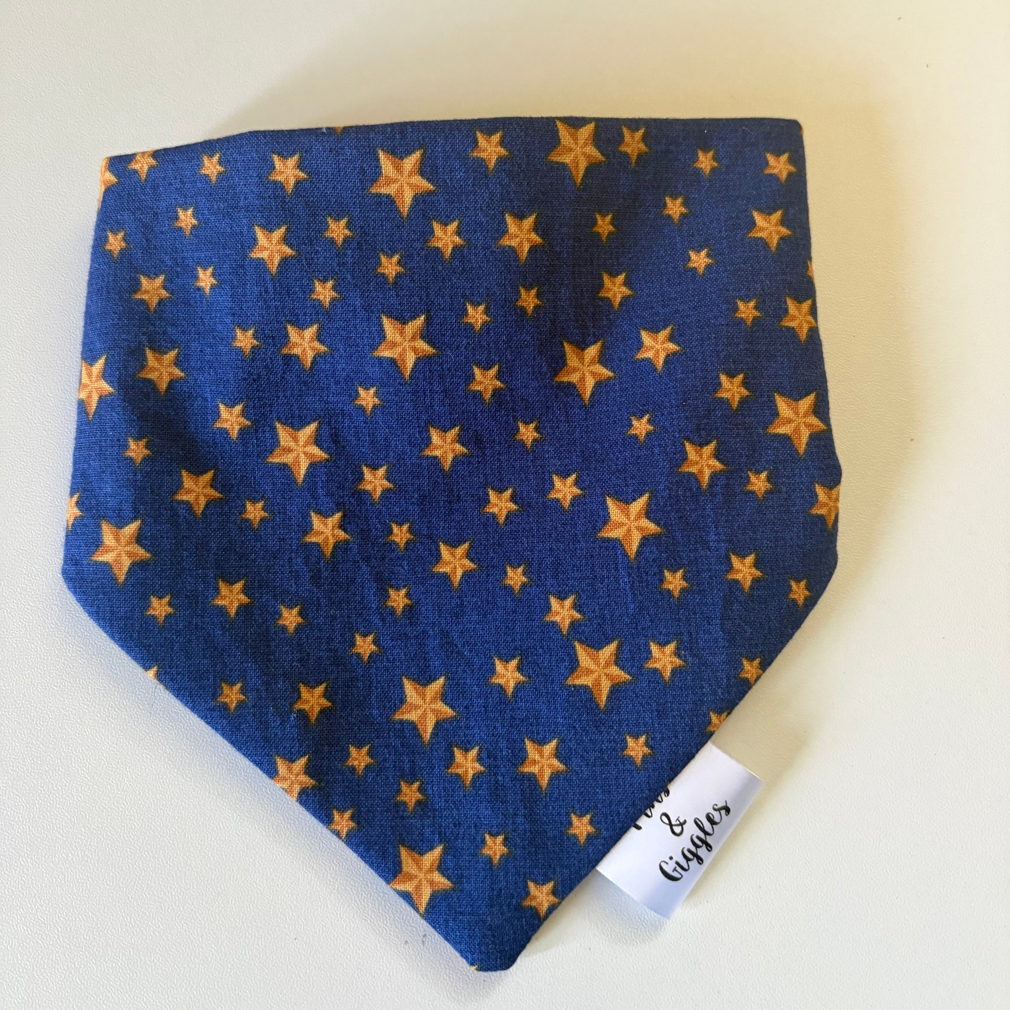 Blue fabric dog bandana with gold star pattern on a white background