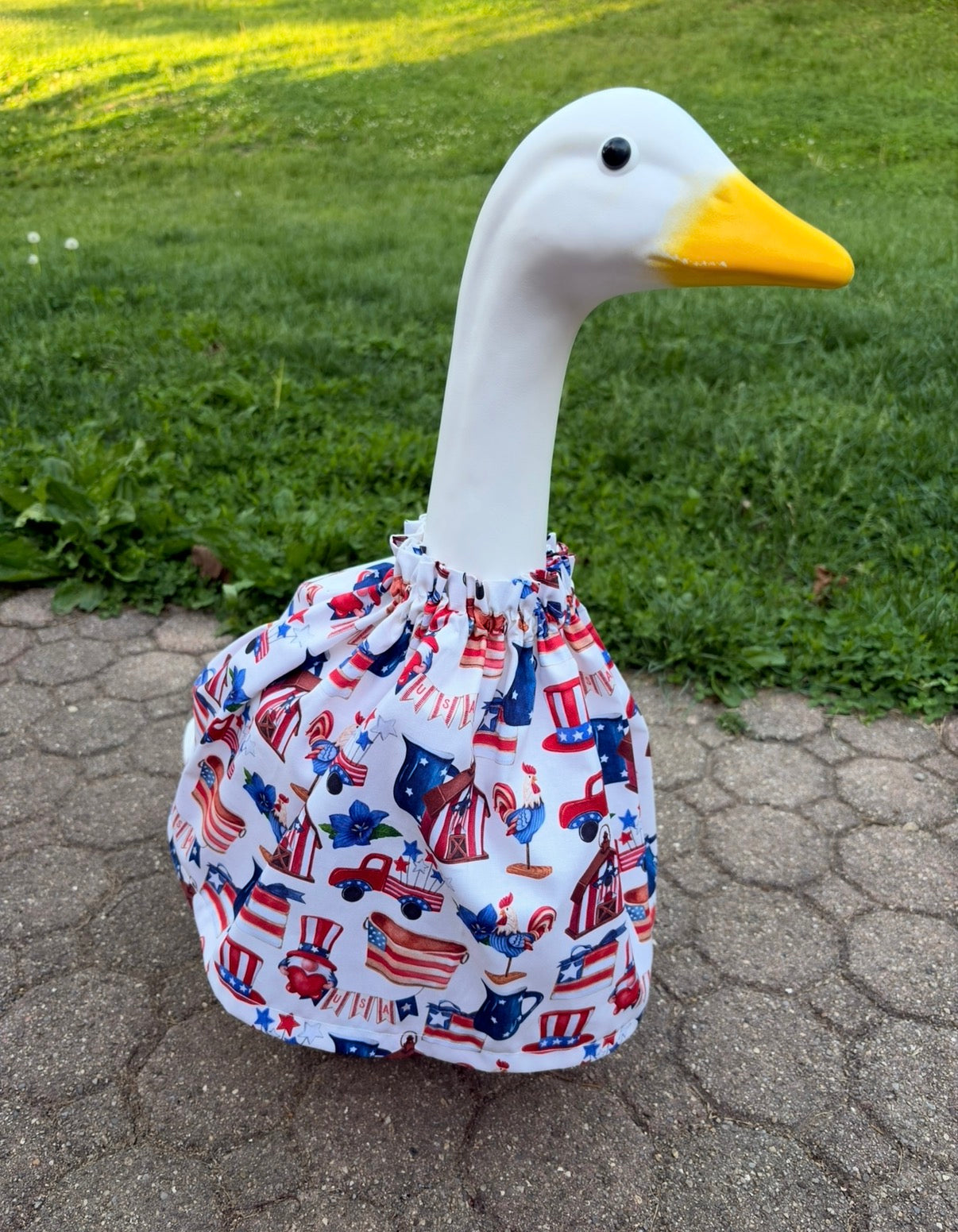 White porch goose wearing a cartoon memorial day themed dress on a grassy background