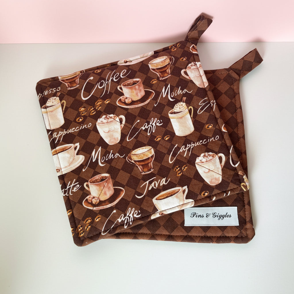Pair of pot holders with coffee-themed design on a white surface