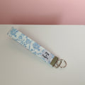 Floral patterned keychain on a white surface with a pinkish background