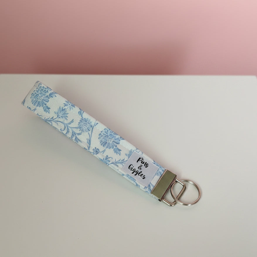 Floral patterned keychain on a white surface with a pinkish background