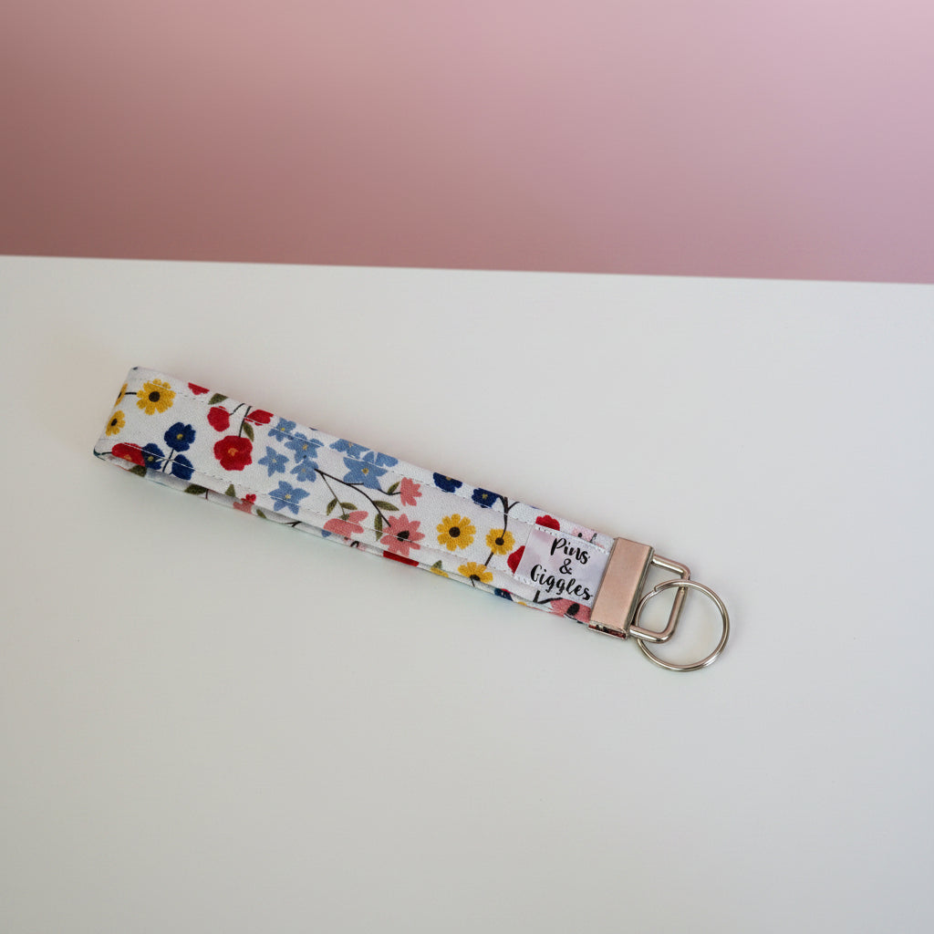 Floral patterned keychain on a white surface with a pink background