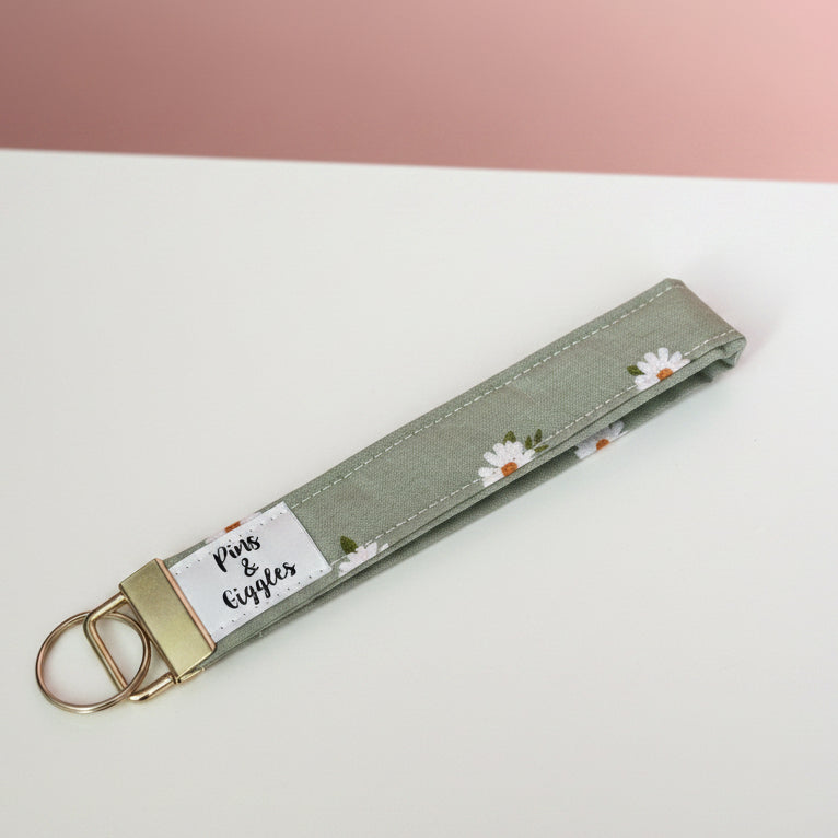 Keychain with floral pattern on a white surface and pink background