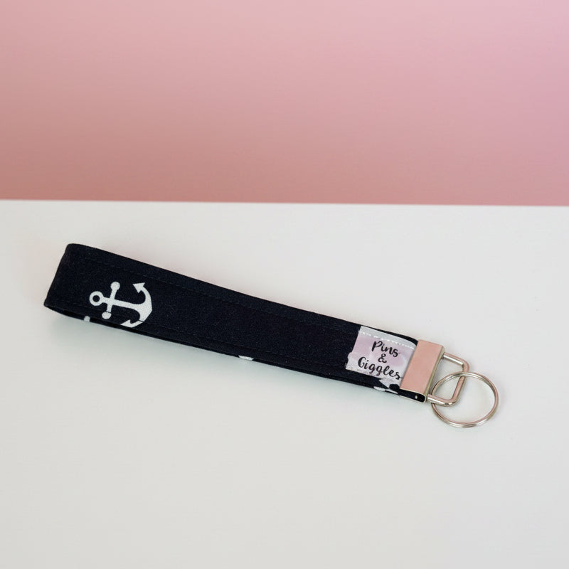 keychain with anchor design on a white surface with a pink background