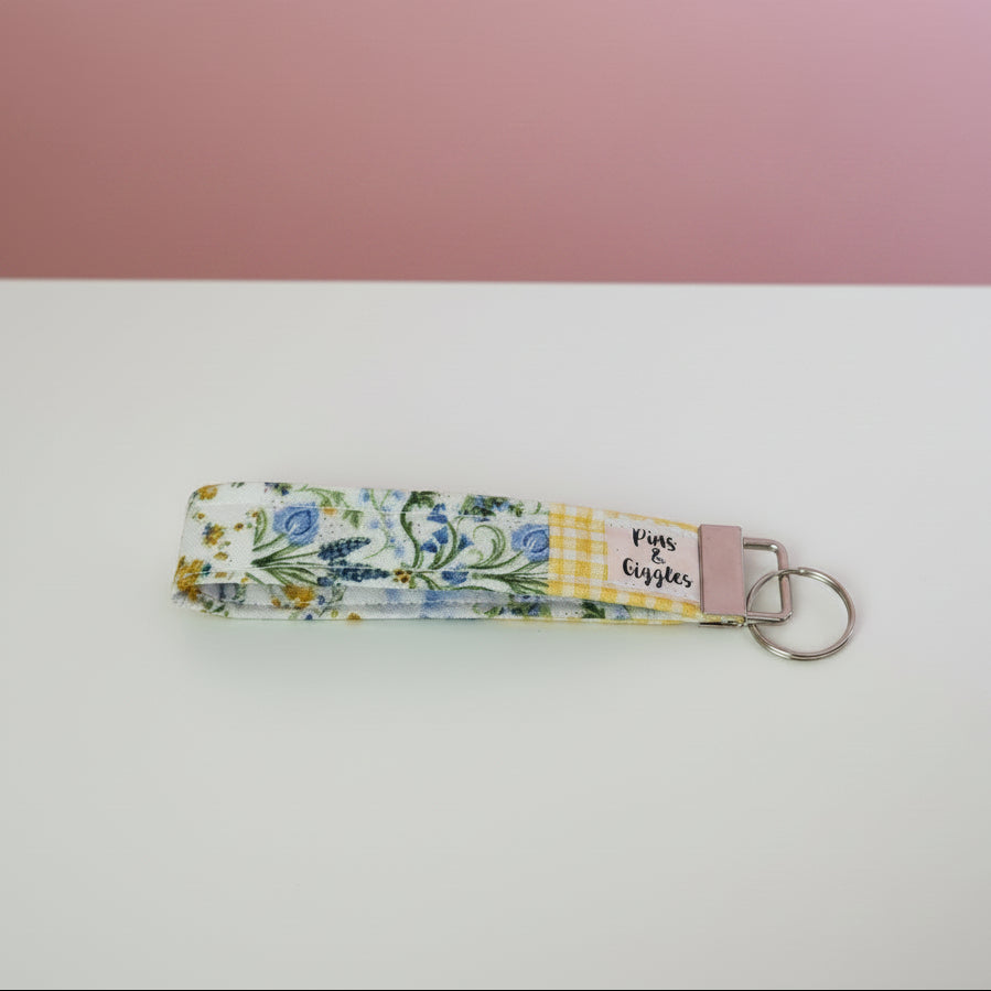 Floral patterned keychain on a white surface with a pink background
